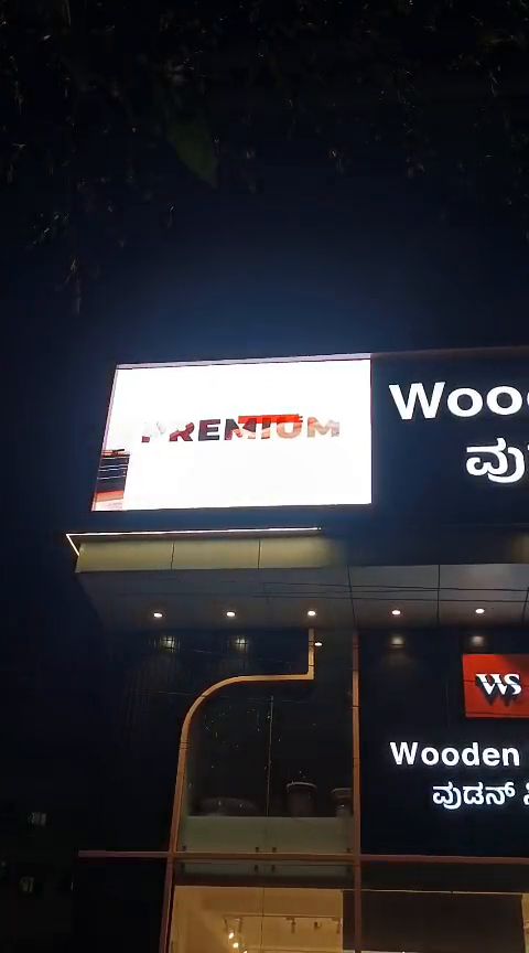 LED display board above a furniture showroom storefront at night, running product visuals