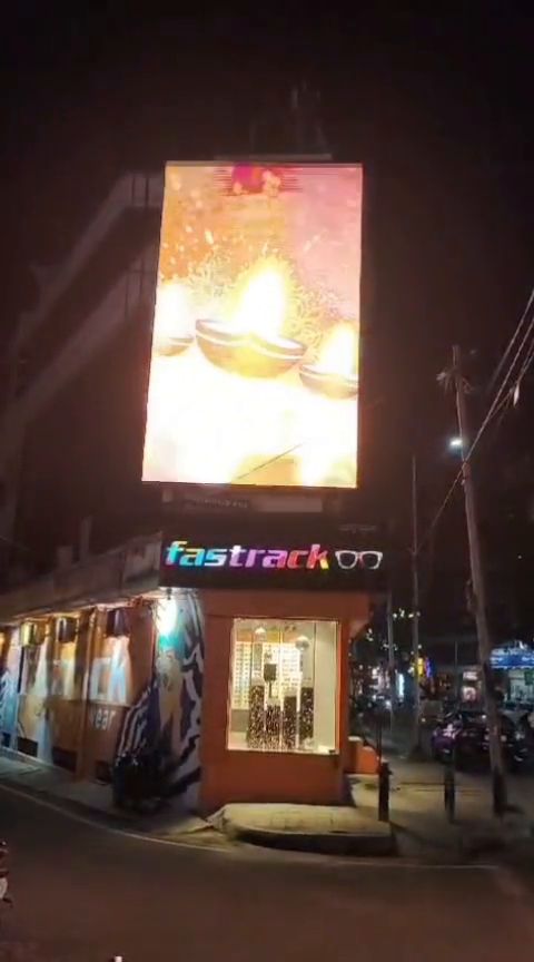 Tall vertical LED display above a corner retail block at night