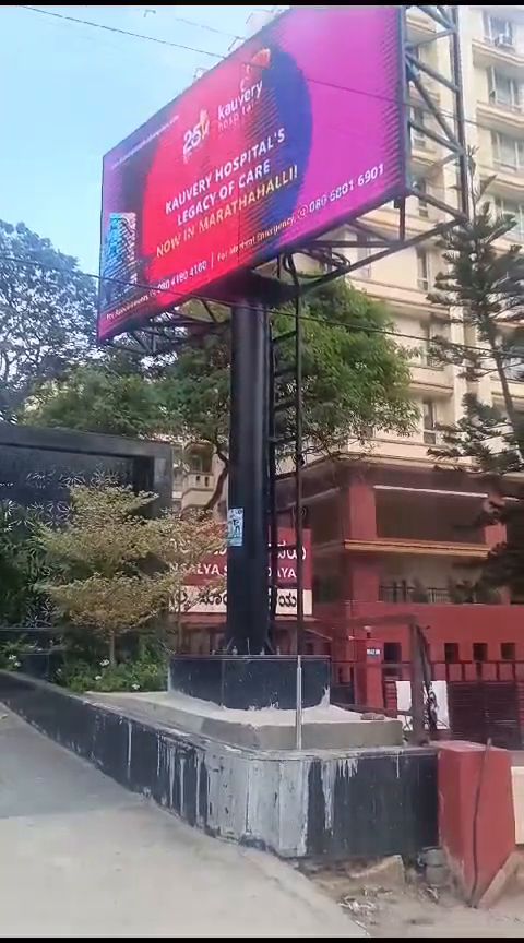 Roadside pole-mounted outdoor LED billboard beside an apartment block