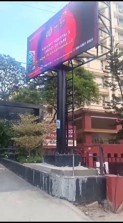 Roadside pole-mounted outdoor LED billboard beside an apartment block