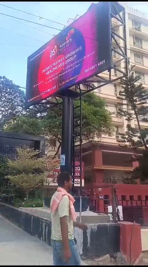 Roadside pole-mounted outdoor LED billboard beside an apartment block