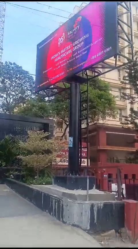 Roadside pole-mounted outdoor LED billboard beside an apartment block