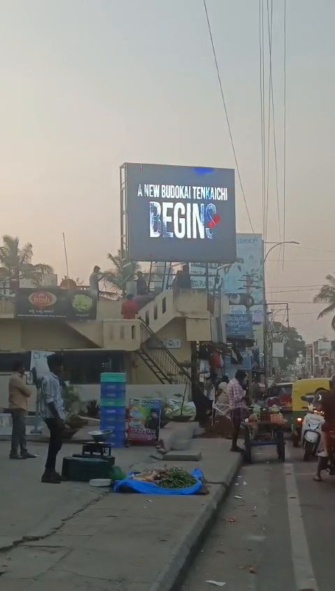 Rooftop outdoor LED screen above a busy street market at dusk