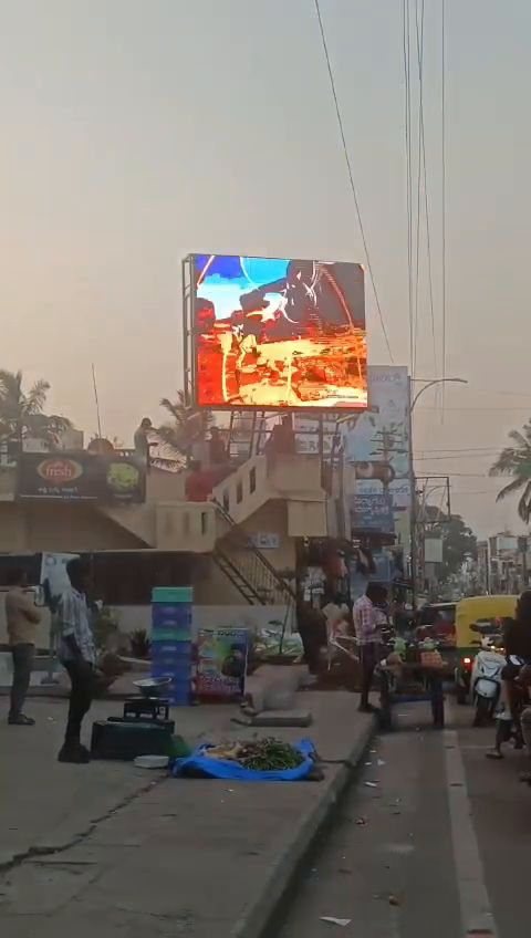 Rooftop outdoor LED screen above a busy street market at dusk