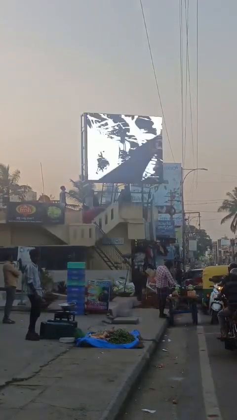 Rooftop outdoor LED screen above a busy street market at dusk