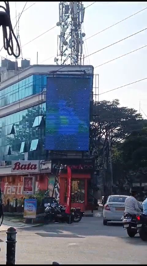 Vertical LED display mounted on a commercial building facade in daylight