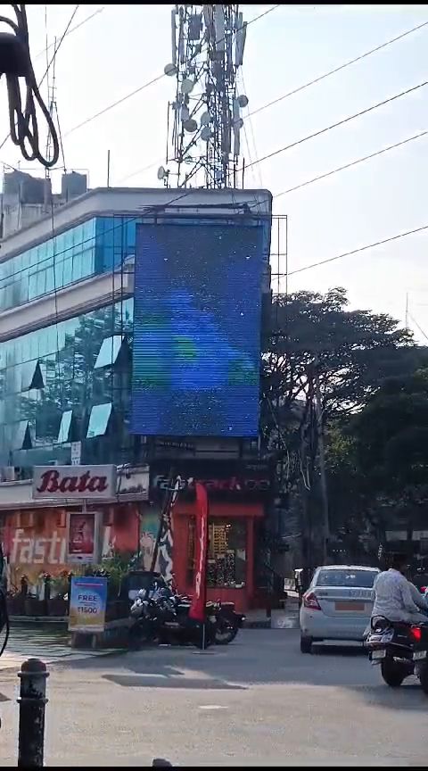 Vertical LED display mounted on a commercial building facade in daylight