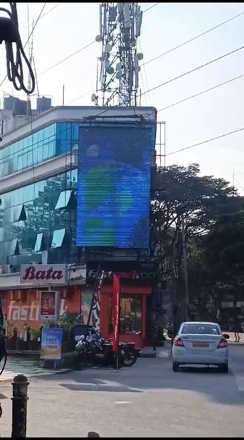 Vertical LED display mounted on a commercial building facade in daylight