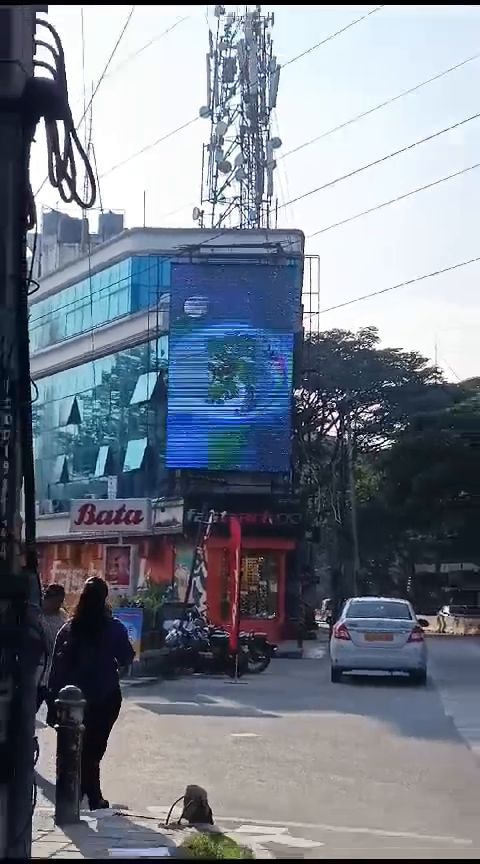 Vertical LED display mounted on a commercial building facade in daylight