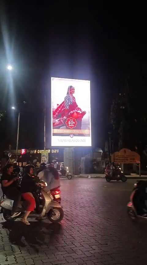 Freestanding vertical LED billboard at a road junction at night