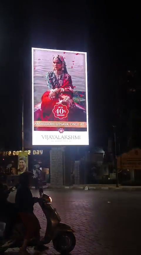 Freestanding vertical LED billboard at a road junction at night