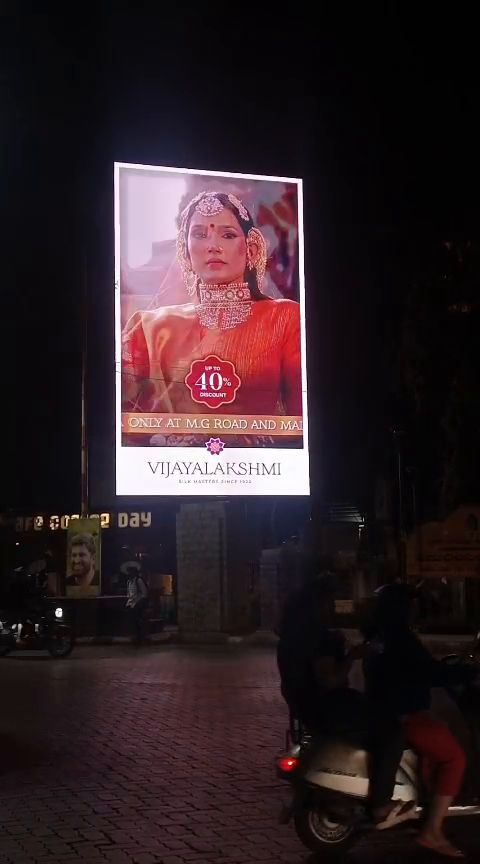 Freestanding vertical LED billboard at a road junction at night