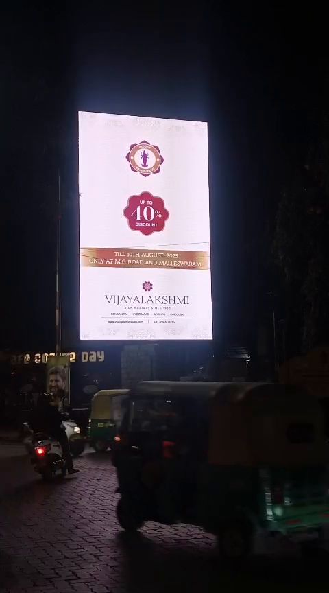 Freestanding vertical LED billboard at a road junction at night