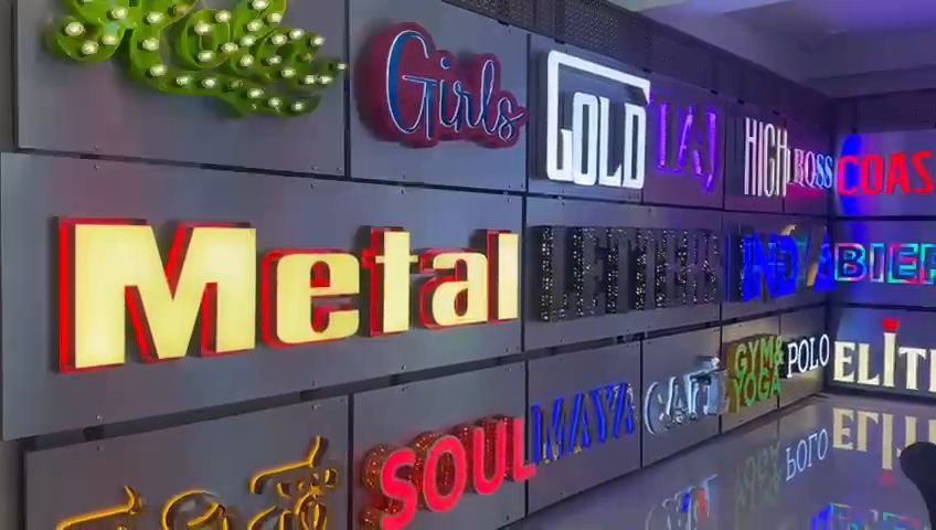 Showroom wall of illuminated channel letters and LED neon lettering in English and Kannada