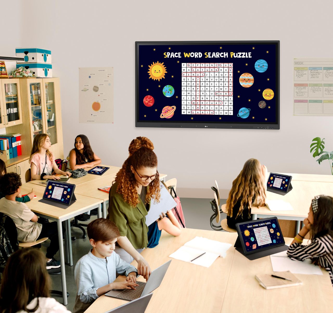 Classroom using an LG CreateBoard with pupils working on tablets at shared desks