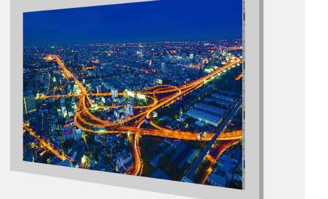 Slim wall-mounted LED panel in a thin frame showing a night cityscape